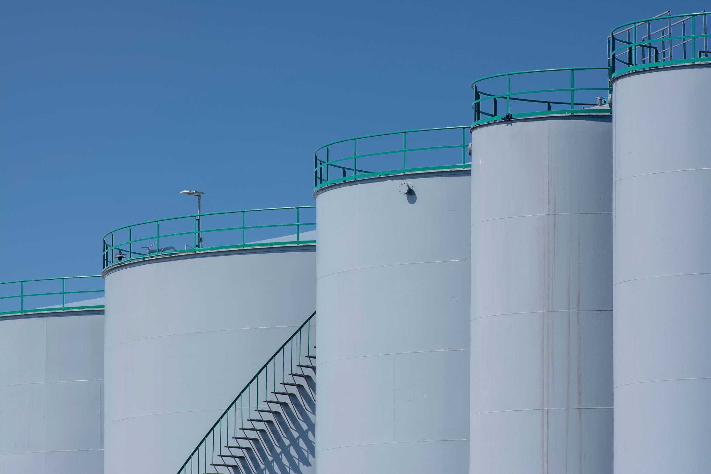 White lubricant storage tanks against a blue sky