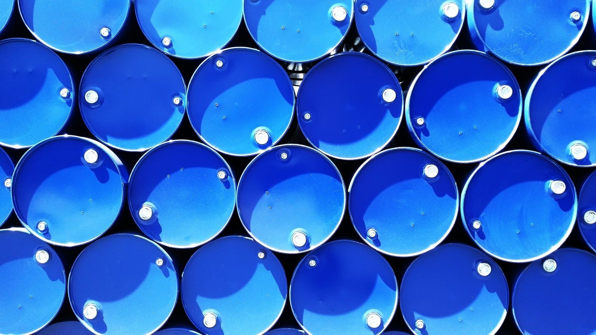 Rows of blue 208-litre drums seen from above
